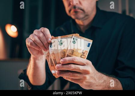 Homme d'affaires comptant cinquante billets en euros tard dans la nuit dans son bureau, focus sélectif Banque D'Images