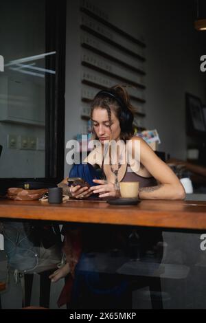 Femme hippie élégante dans un café avec un téléphone. Banque D'Images