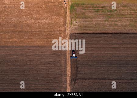 Tracteur avec équipement de timon labourant le sol des terres agricoles, tir aérien de haut en bas Banque D'Images