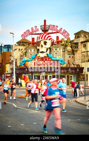 Flou de mouvement des concurrents dans le Blackpool 10K Funrun passant devant le centre d'amusement Coral Island(2024) Banque D'Images