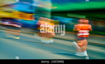 Flou de mouvement des concurrents dans le Blackpool 10K fun run(2024) le long d'une promenade colorée Banque D'Images