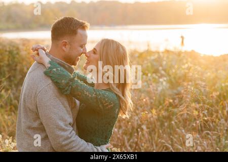 Couple romantique embrassant dans le champ au coucher du soleil Banque D'Images