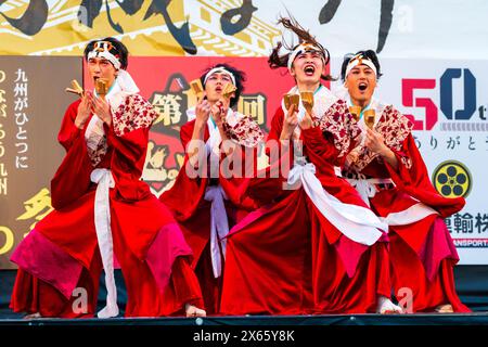 Groupe de quatre danseurs yosakoi adolescents sur scène chantant et tenant naruko, des clapets en bois, pendant le festival de danse Kumamoto Kyusyu Gassai. Banque D'Images