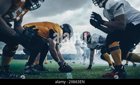 Championnat américain de football. Équipes prêtes : joueurs professionnels, affrontement agressif, prêt à pousser, attaquer. Compétition pleine d'énergie brutale, de puissance. Photographié avec une lumière dramatique Banque D'Images