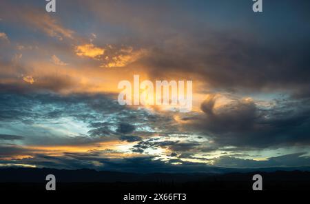 Scène de coucher de soleil dramatique. Le ciel est rempli de nuages et le soleil se couche. Le ciel est plein de nuages avec un mélange de bleu et d'orange. Banque D'Images