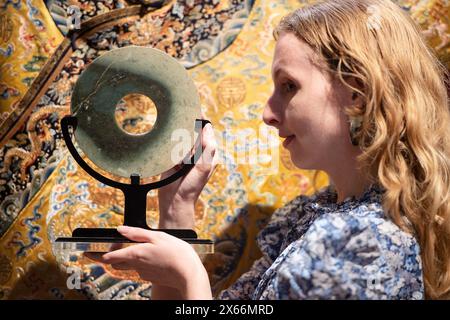 Londres, Angleterre, Royaume-Uni. 13 mai 2024. Un membre du personnel de Bonhams tient un disque de jade, Bi, de la période néolithique, d'une valeur estimée de Â£2 000 à Â£3 000, lors d'un appel photo à Bonhams Londres. (Crédit image : © Thomas Krych/ZUMA Press Wire) USAGE ÉDITORIAL SEULEMENT! Non destiné à UN USAGE commercial ! Crédit : ZUMA Press, Inc/Alamy Live News Banque D'Images