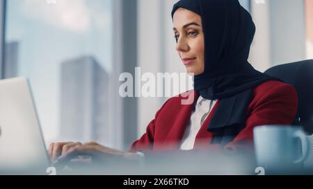 Gros plan Portrait de magnifique femme d'affaires musulmane portant Burka assis à son bureau travaillant sur un ordinateur portable au bureau. Stratégie d'investissement du plan directeur général d'entreprise réussie pour le démarrage du commerce électronique Banque D'Images