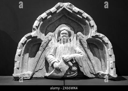 Photo en noir et blanc d'une partie de sculpture médiévale en marbre de l'église italienne représentant et ange sous une arche tenant un long morceau de papier Banque D'Images