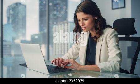 Portrait de jeune femme d'affaires caucasienne réussie assise au bureau travaillant sur ordinateur portable dans le bureau de la ville. Belle et talentueuse directrice générale Plan Stratégie de médias sociaux pour le projet de commerce électronique Banque D'Images