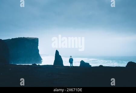 Femme touriste stand dans une journée très venteuse regarder les vagues de l'océan Atlantique s'écraser sur les rochers sur la côte de la péninsule de Reykjanes en Islande. Locatio nature pittoresque populaire Banque D'Images