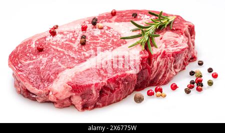 Steak de ribeye cru avec des grains de poivre et romarin isolé sur fond blanc. Banque D'Images