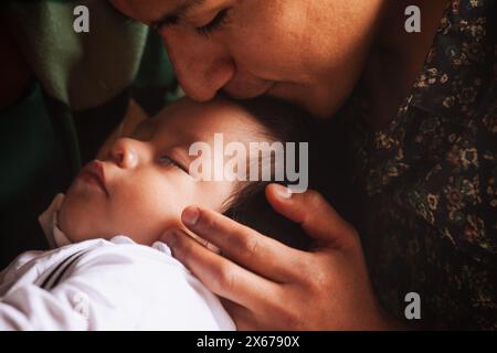 Un moment intime d'un père embrassant son bébé endormi, capturant l'essence de l'amour paternel et des soins. Banque D'Images