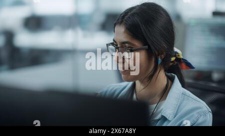 Bureau diversifié : Portrait de beau programmeur INFORMATIQUE indien travaillant sur ordinateur de bureau. Spécialiste féminin portant des lunettes créez un logiciel innovant. Ingénieur professionnel développer une application inspirante Banque D'Images