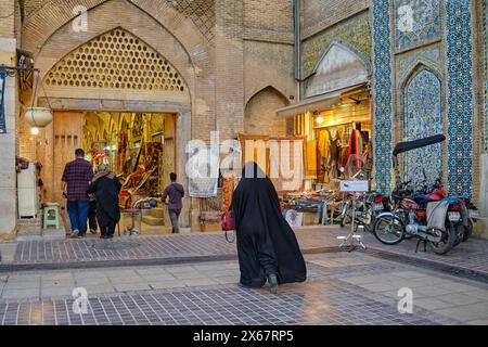 Une femme iranienne portant un tchador noir traditionnel marche vers l'entrée du bazar de Vakil à Shiraz, en Iran. Banque D'Images