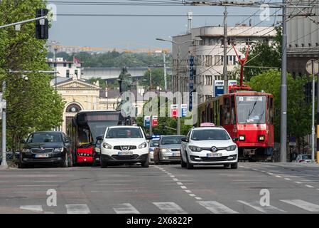 La circulation s'alignait sur la rue Nemanjina à Belgrade. Voitures, taxi, bus et tram avec l'ancienne gare au loin. Mai 2024. Banque D'Images