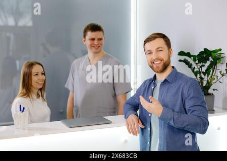 Patient reconnaissant. Homme debout à la réception de la clinique dentaire et très heureux pour le traitement Banque D'Images