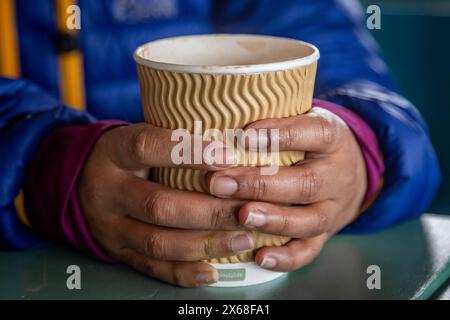 Un gros plan d'une femme méconnaissable mains tenant une tasse de papier avec une boisson chaude dedans Banque D'Images