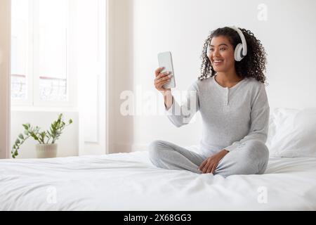 Sourire jeune femme en tenue décontractée s'engageant dans un appel vidéo Banque D'Images