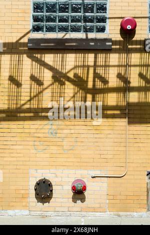 Une bouche d'incendie rouge se trouve sur le côté d'un bâtiment. L'ombre de la bouche d'incendie est projetée sur le mur Banque D'Images