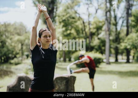 Homme et femme s'étirant pendant l'entraînement en plein air dans un parc verdoyant luxuriant Banque D'Images