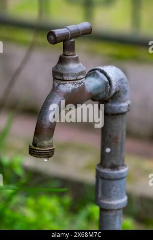 Un robinet rouillé coule de l'eau. L'eau tombe du robinet et sur le sol Banque D'Images