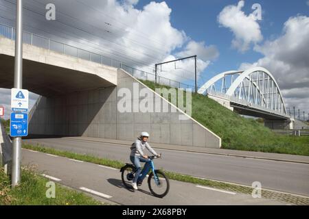 Cycliste utilisant une piste cyclable passant sous un pont de chemin de fer sur le canal Albert près de Hasselt, Belgique. Banque D'Images