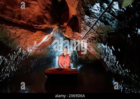 Spéléologue traverse un lac souterrain dans un canot en caoutchouc Banque D'Images