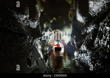 Spéléologue traverse un lac souterrain dans un canot en caoutchouc Banque D'Images