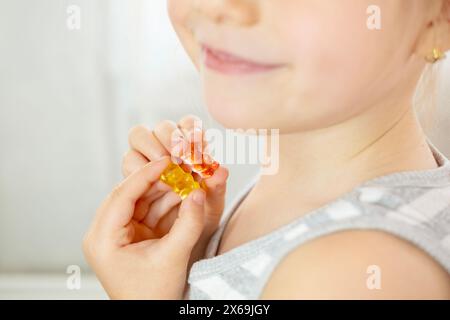 gros plan enfant d'âge préscolaire, fille de 5 ans veut manger des bonbons gélatineux, ours en gomme, enfant a bon appétit, enfance heureuse, alimentation équilibrée, vie douce, Banque D'Images