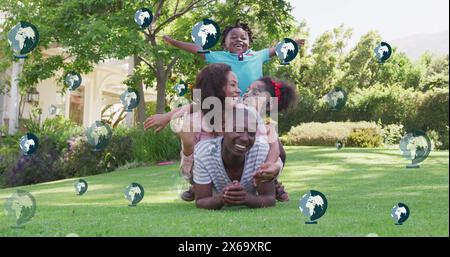 Image d'icônes de globe sur la famille afro-américaine dans le jardin Banque D'Images