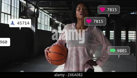 Femme biraciale tenant le basket-ball, portant un haut de sport rose Banque D'Images