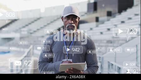 Image des icônes de notification avec des numéros changeants sur l'entraîneur afro-américain utilisant la tablette Banque D'Images