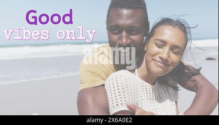 Image des mots bonnes vibrations seulement en violet sur couple heureux embrassant sur la plage Banque D'Images