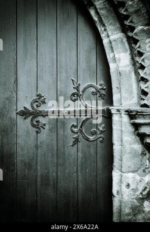 Charnière en fer forgé ornée sur la vieille porte de l'église en bois. Église paroissiale de Saint Lawrence, Appleby, Cumbria, Angleterre Banque D'Images