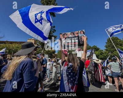 Palo Alto, Californie, États-Unis 12 mai 2024. Israël et les drapeaux américains flottant et une femme juive tenant un panneau, 'n'oubliez pas leurs visages: des adolescents en captivité », et comme des centaines de Juifs sont rejoints par des hindous, des musulmans, des Chinois et d'autres alliés lors d'un contre-rassemblement à l'Université de Stanford le jour de l'indépendance d'Israël et la fête des mères lors d'un rassemblement interreligieux organisé par un groupe d'étudiants juifs. C'était au bout de la place Blanche, où les manifestants pro-palestiniens ont installé un campement de tentes et organisaient un rassemblement où ils appelaient à l'"Intifada" contre Israël, se moquaient des Juifs Banque D'Images