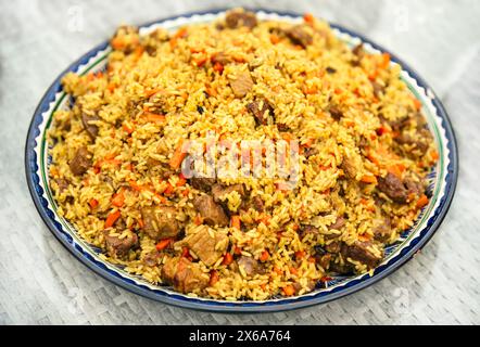 Plat national de la cuisine orientale des pays d'Asie centrale pilaf (plov) avec viande de porc et de bœuf dans l'assiette Banque D'Images