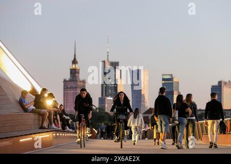 Varsovie, Pologne. 13 mai 2024. On voit des gens marcher le long du nouveau pont piétonnier et cycliste qui traverse la Vistule. Le nouveau pont piétonnier et cyclable sur la Vistule mesure 452 mètres de long et relie le centre-ville au quartier de Praga. Il a été ouvert le 28 mars 2024 et est devenu très populaire parmi les résidents de la ville et les touristes. Depuis le pont, les piétons et les cyclistes peuvent profiter de la vue sur la Vistule et Varsovie, y compris le centre historique - un site classé au patrimoine mondial de l'UNESCO. Crédit : SOPA images Limited/Alamy Live News Banque D'Images