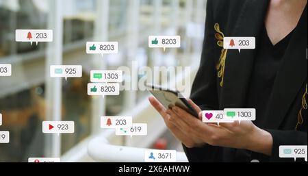 Image des icônes de message avec des numéros changeants sur la section médiane de la femme caucasienne utilisant un téléphone portable Banque D'Images