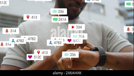 Image d'icônes de médias sociaux tombant au milieu de la section d'un homme utilisant smartwatch à l'extérieur Banque D'Images