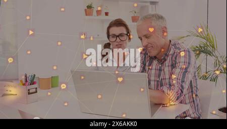 Réseau d'icônes numériques contre un couple de personnes âgées caucasiennes utilisant un ordinateur portable ensemble à la maison Banque D'Images