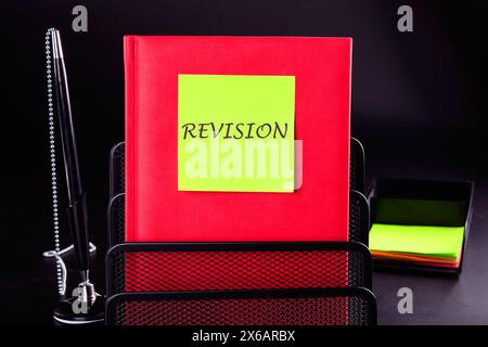 Symbole de révision conceptuelle. Mot DE RÉVISION écrit sur un autocollant jaune sur un bloc-notes rouge devant un fond noir. Un emplacement à copier Banque D'Images