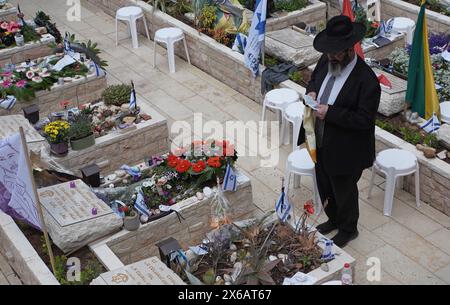 JÉRUSALEM - 12 MAI : un juif ultra-orthodoxe prie alors qu'il se tient debout près de la tombe d'un soldat tombé au cimetière militaire national du Mont Herzl alors que le pays se prépare à célébrer la Journée commémorative Yom Hazikaron pour les soldats tombés au combat le 12 mai 2024 à Jérusalem. Israël Banque D'Images