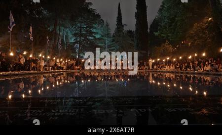 JÉRUSALEM - 12 MAI : les éclaireurs israéliens allument des torches, lors d'une cérémonie à l'occasion du jour commémoratif de Yom Hazikaron pour les soldats tombés au combat, au-dessus de la piscine commémorative des 140 soldats juifs qui se sont noyés à bord du SS Erinpura en Méditerranée le 1er mai 1943, par des bombardiers allemands pendant la seconde Guerre mondiale au cimetière militaire national du mont Herzl le 12 mai 2024 à Jérusalem. Israël Banque D'Images