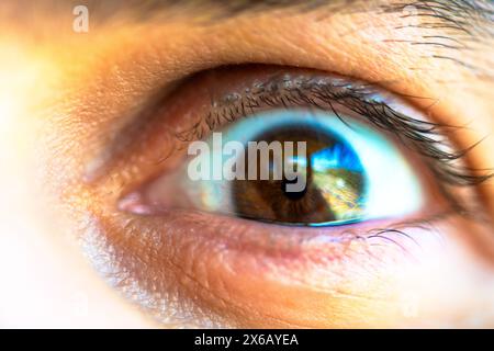 Une photo macro captivante révélant les détails complexes de l'œil brun d'un homme, évoquant la profondeur et l'émotion. Banque D'Images