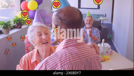 Image d'icônes de coeur sur divers amis seniors dansant Banque D'Images