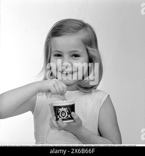 La crème glacée dans les années 1960 Une jeune fille mange de la crème glacée avec une cuillère dans une tasse en papier. 1961 Kristoffersson réf CS97-4 Banque D'Images