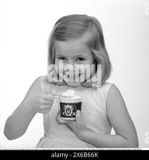 La crème glacée dans les années 1960 Une jeune fille mange de la crème glacée avec une cuillère dans une tasse en papier. 1961 Kristoffersson réf CS96-1 Banque D'Images