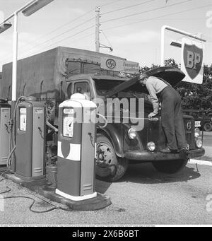 Station-service dans les jours anciens. Ici, un chauffeur de camion de la société ASG s'est arrêté et a ouvert le capot de son camion Volvo. La station-service appartient à la compagnie pétrolière anglaise BP (British Petroleum). Les activités de la société avec ses propres stations-service en Suède ont été interrompues en 1994 et la plupart des stations-service BP sont devenues des stations-service Statoil. 1959. Roland Palm réf. 10-72-5 Banque D'Images