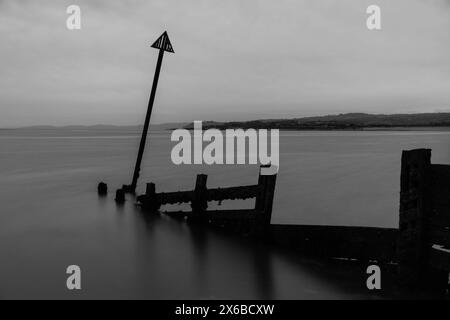 Marqueur de mer triangulaire à l'extrémité d'un groyne en bois en décomposition, Exmouth Devon UK. Mars 2024 Banque D'Images