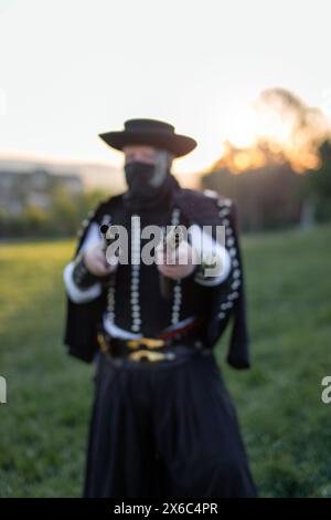 Homme hors-la-loi hongrois betyar dans un masque noir pointant des fusils de chasse au coucher du soleil à l'extérieur Banque D'Images